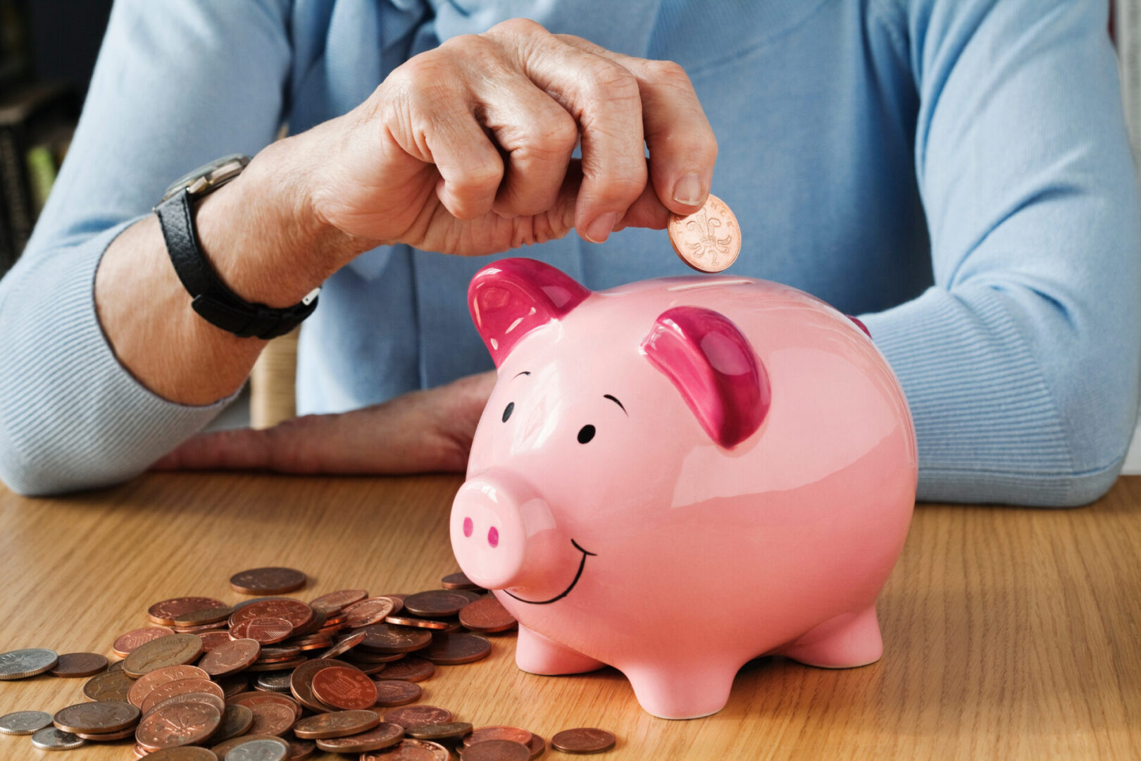 senior woman inserting coins into piggybank